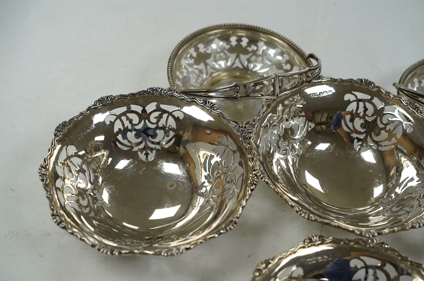 A set of four George VI pierced silver bonbon dishes, by Mappin & Webb, Sheffield, 1938, diameter 12cm and an earlier pair of silver bonbon baskets, 15.7oz. Condition - fair